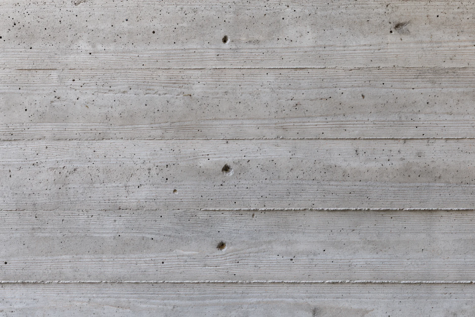 Flat concrete wall surface with horizontal texture and speckled grain filling the frame