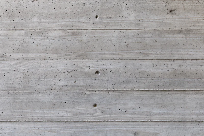 Flat concrete wall surface with horizontal texture and speckled grain filling the frame