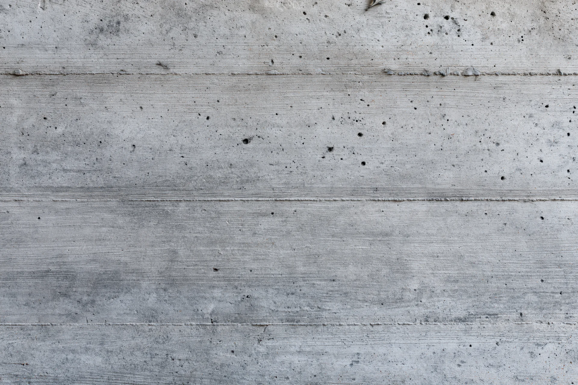 Flat concrete wall surface with horizontal lines and small holes filling the frame