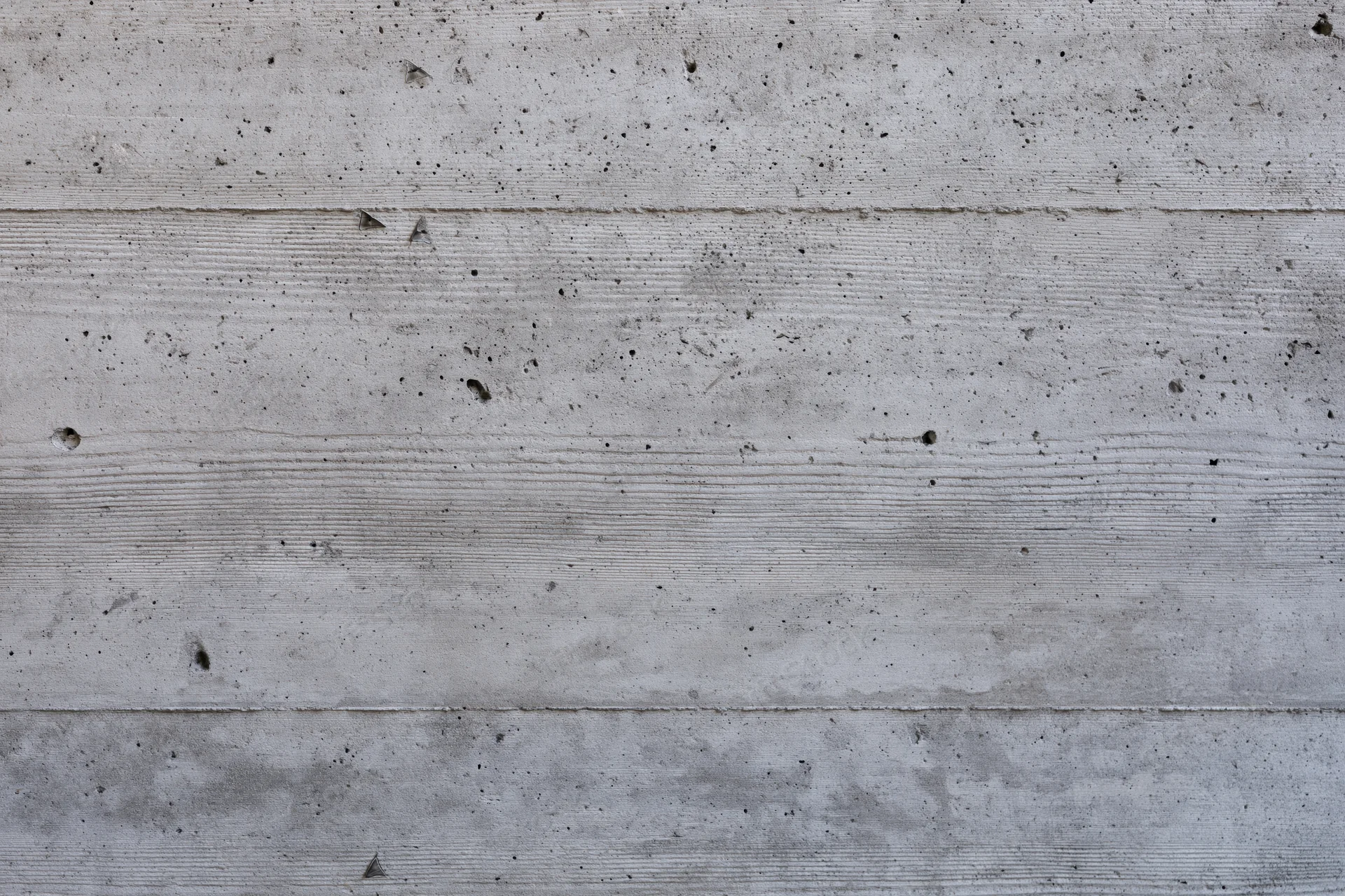 Flat concrete wall surface filling the frame with horizontal panels and textured grain