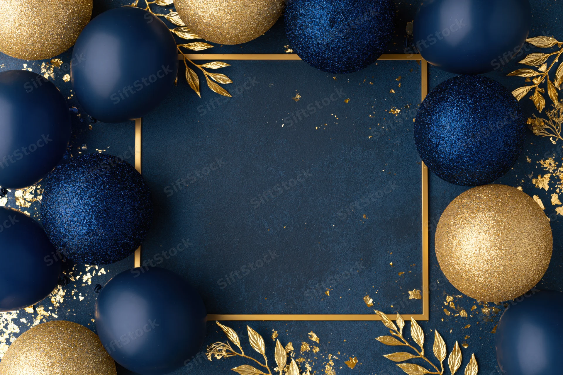 Navy blue and gold ornaments arranged in a flat lay with a gold frame and scattered glitter on a dark blue surface, creating a festive holiday background with copyspace