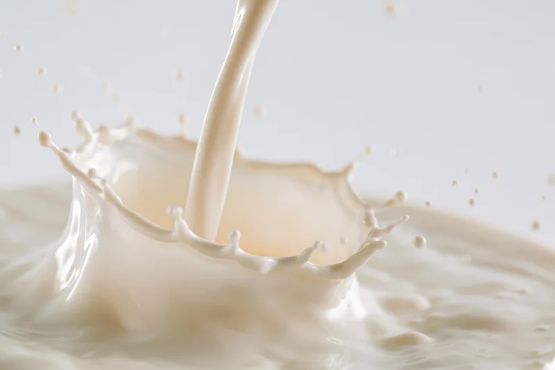 Milk pouring into a pool creating a splash crown against white background