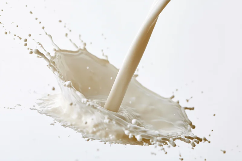 Stream of milk pouring and splashing mid-air against white background