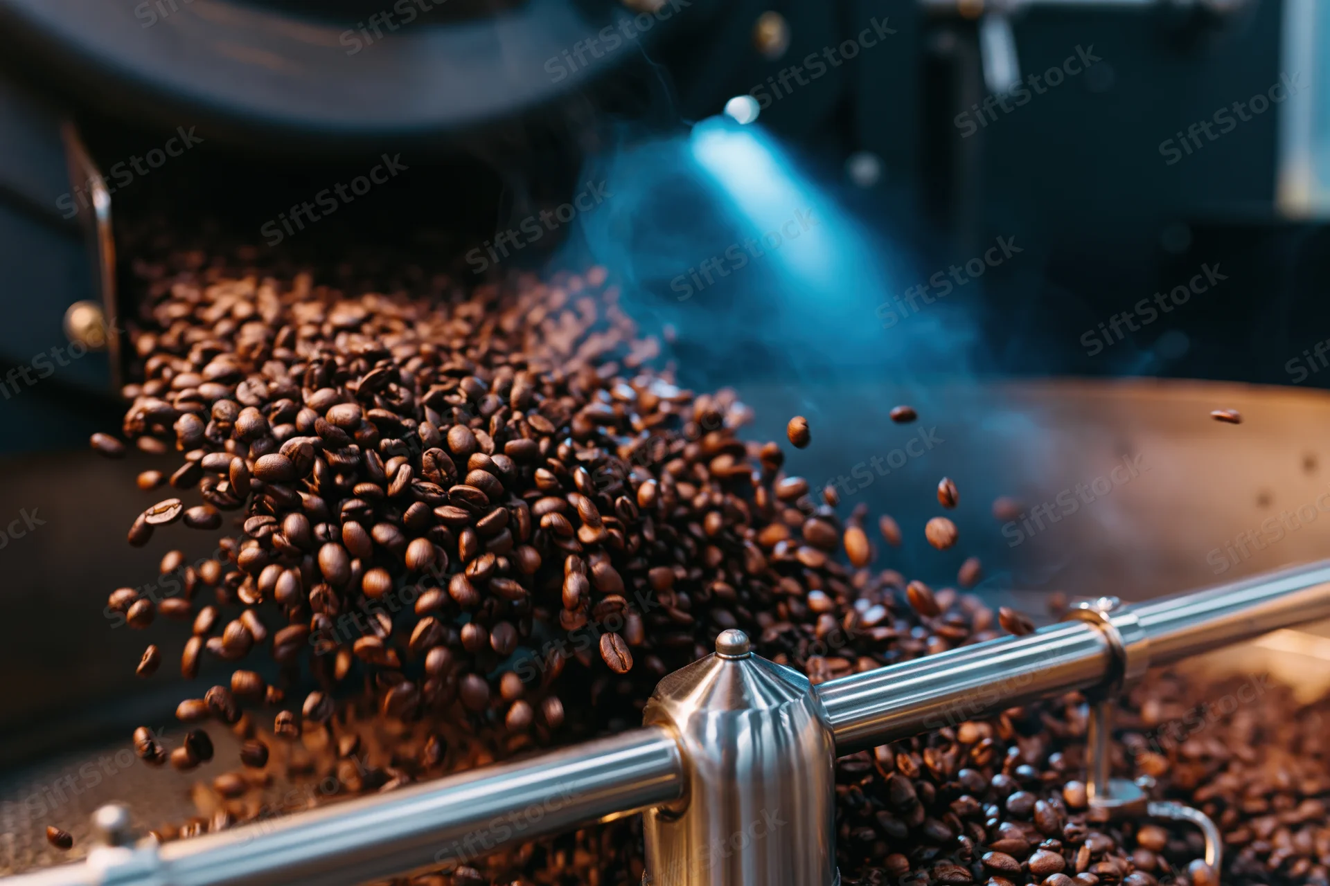 Roasted coffee beans cascading mid-air from industrial roasting machine in factory setting