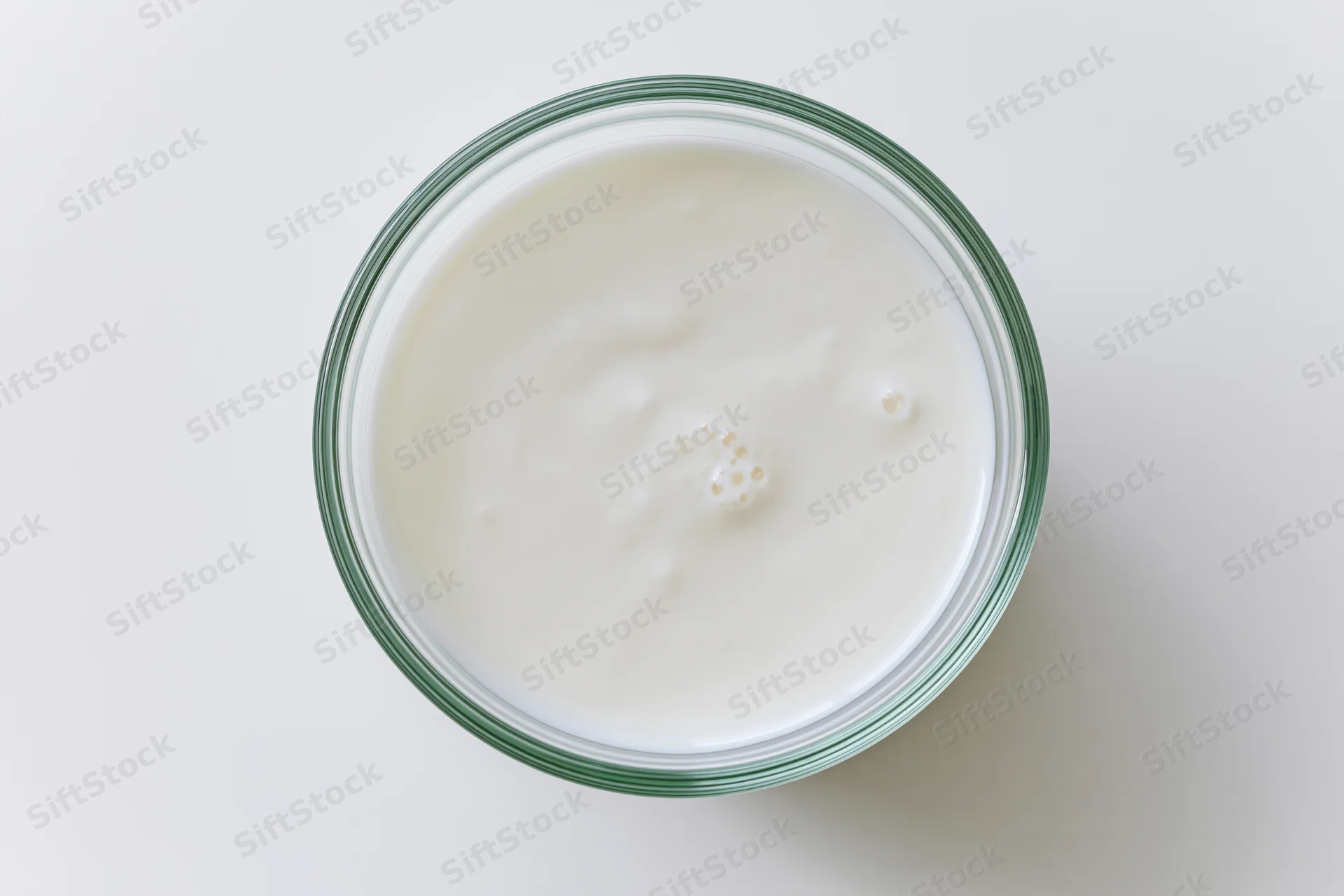Top view of white yogurt in a glass jar on a plain white surface