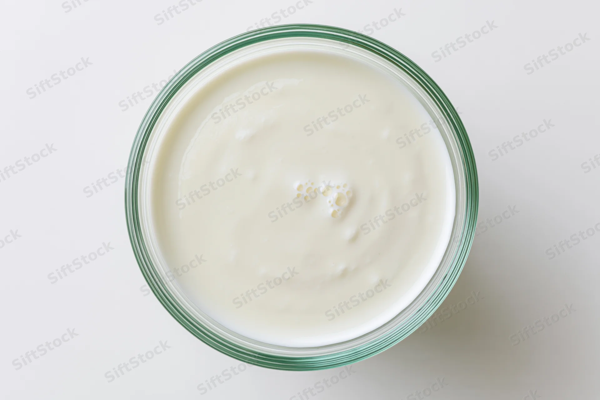 Top view of plain white yogurt in a glass jar on a white surface