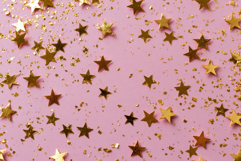Star-shaped confetti and glitter scatter across pink background