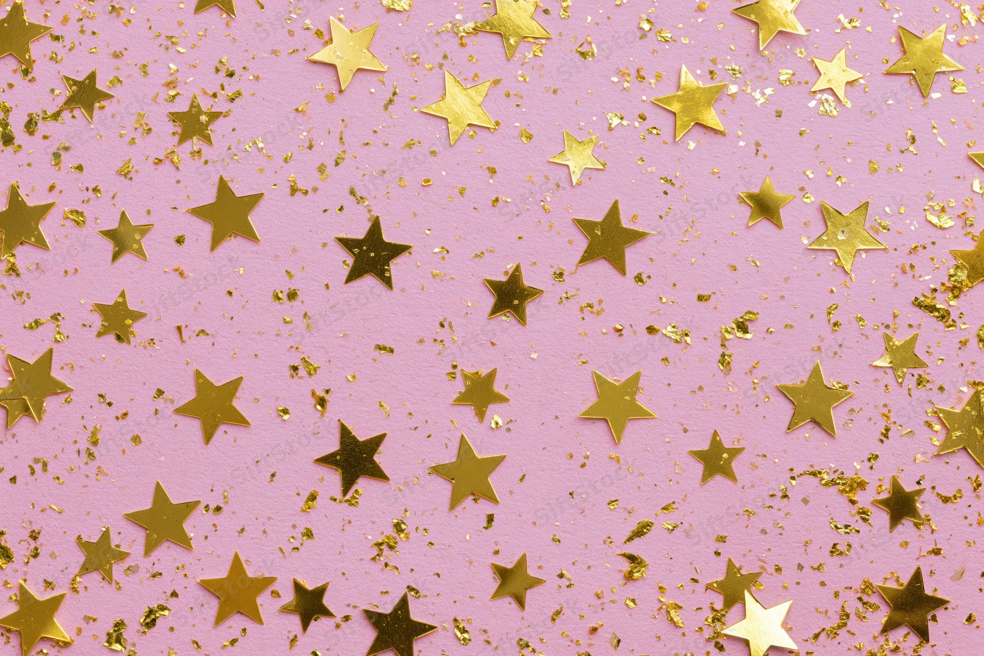 Gold star-shaped confetti and metallic glitter scattered across a pink surface