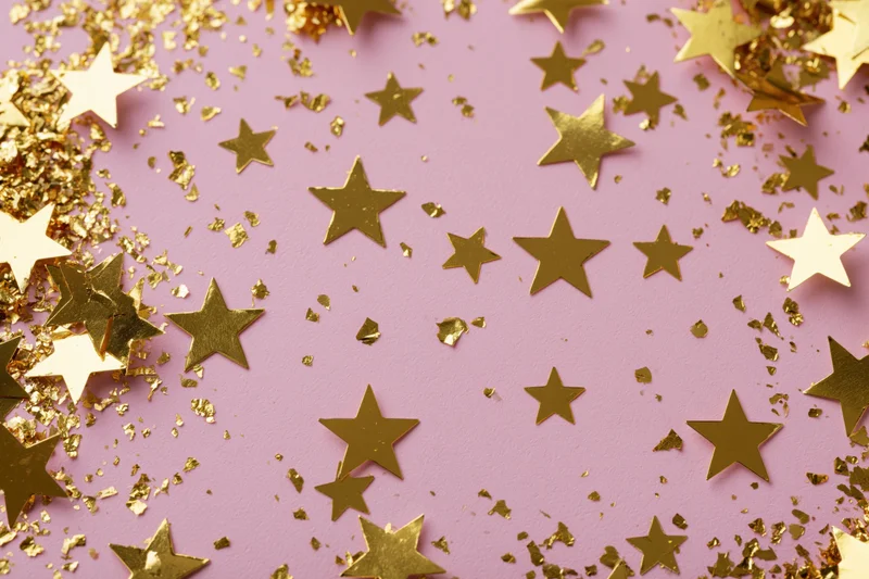 Gold star-shaped confetti and metallic glitter pieces scatter