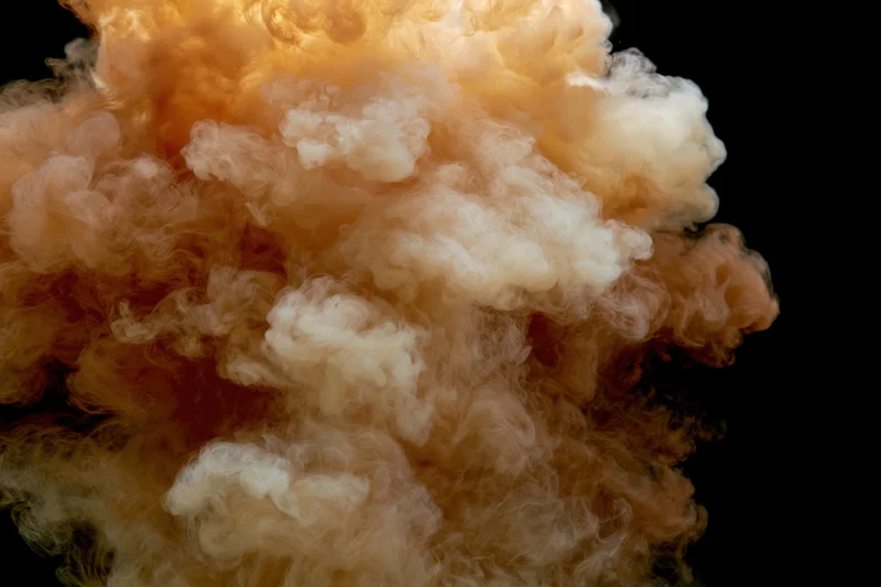 Golden amber ink billowing upward against black background