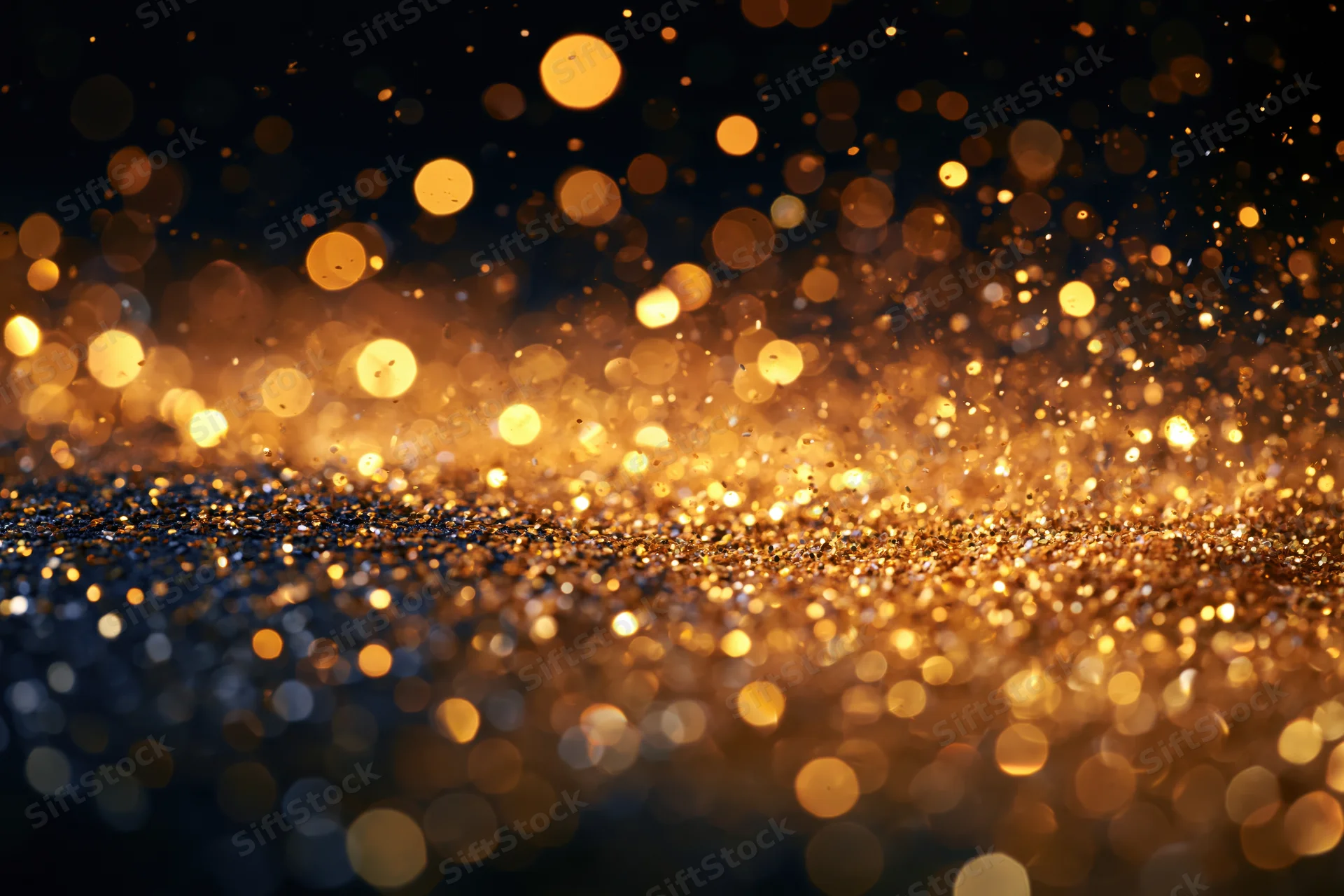 Golden glitter and light particles suspended mid-air against a dark background with bokeh effect