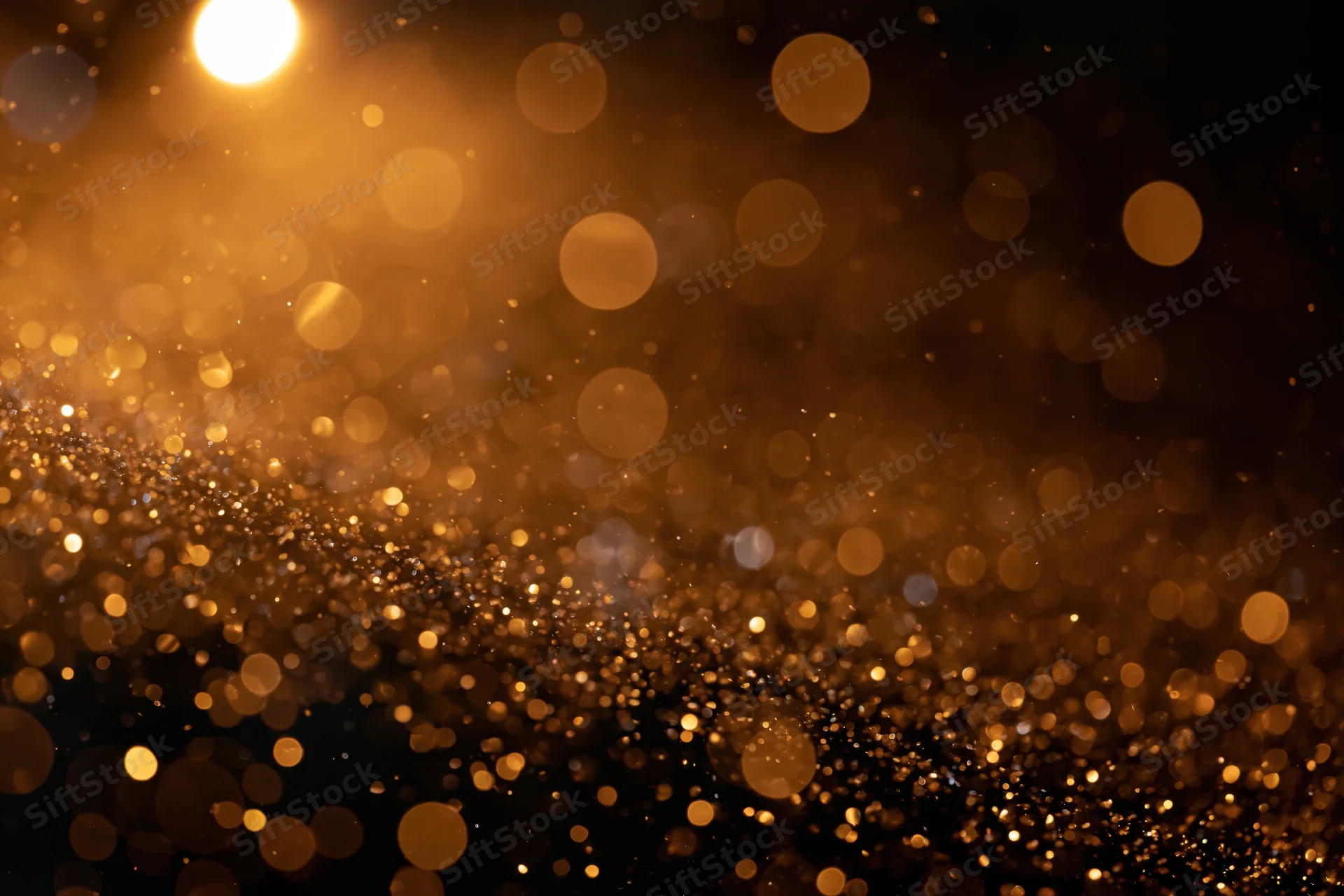 Golden glitter and light particles suspended mid-air against a dark background
