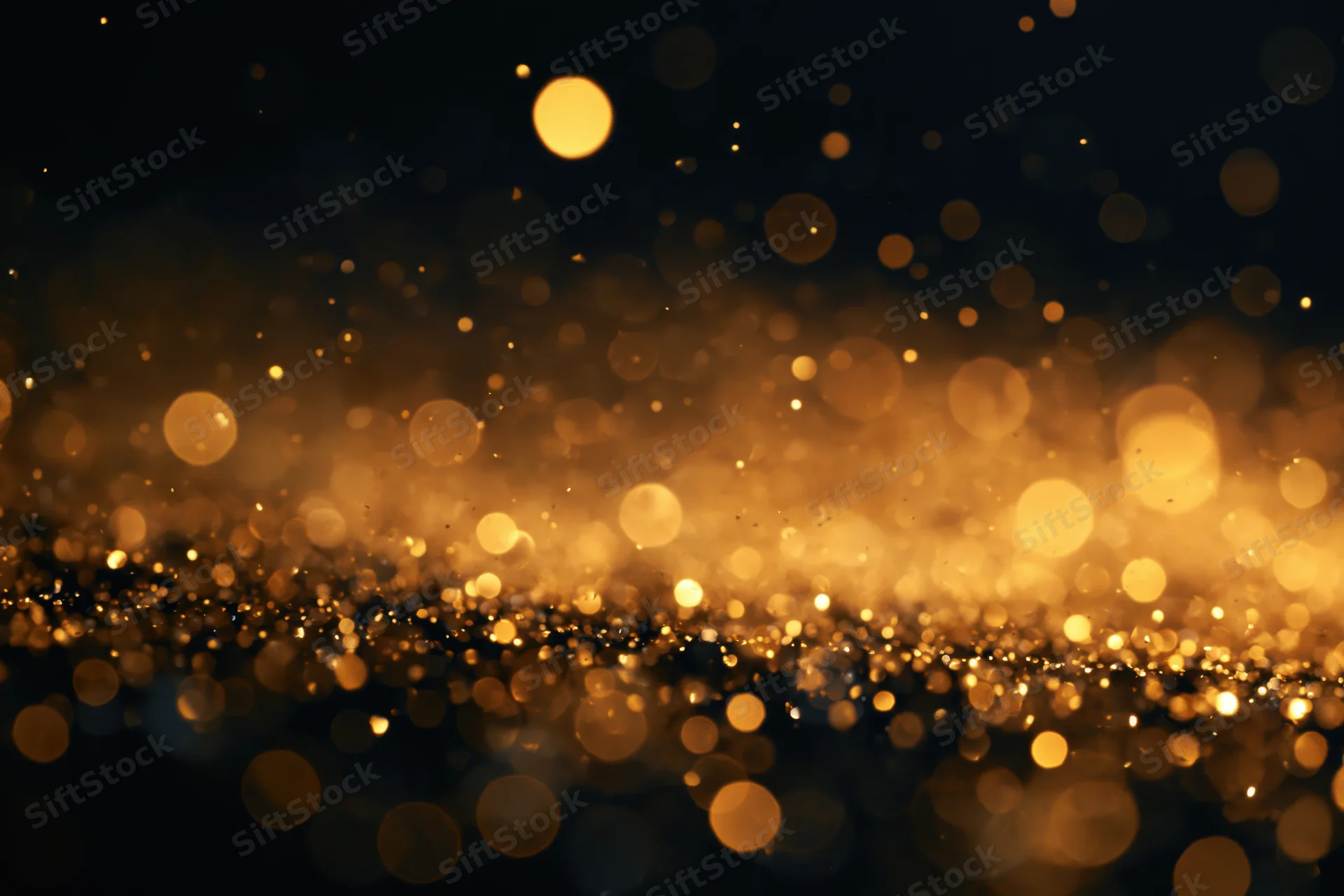 Golden glitter and light particles suspended mid-air against a dark background