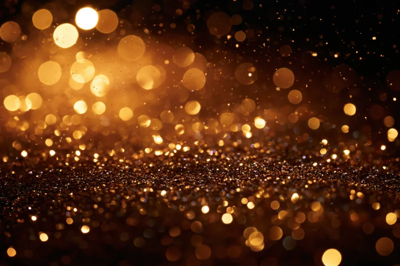 Golden glitter and light particles suspended mid-air against a dark background