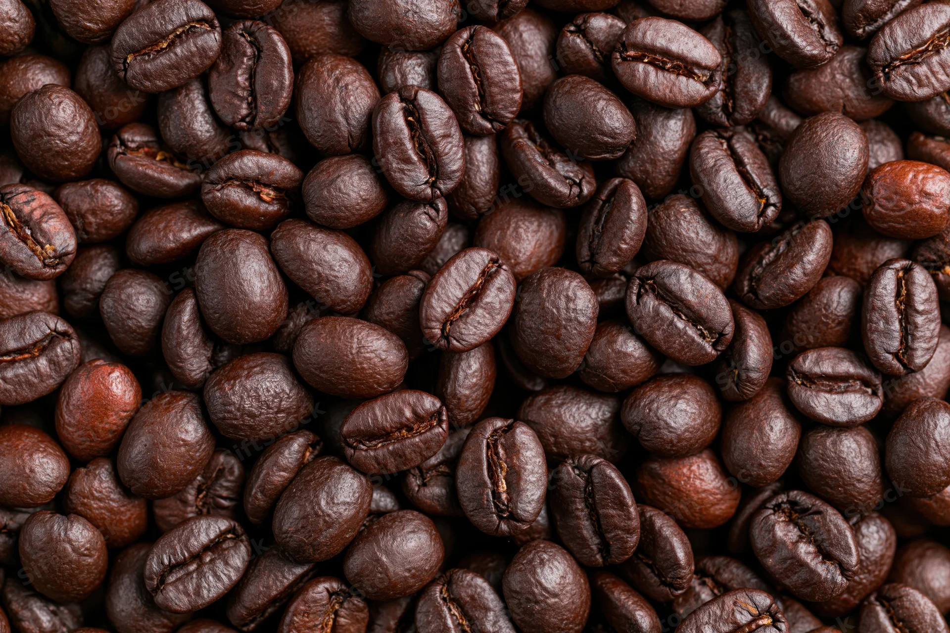Dark roasted coffee beans filling the frame in a closeup texture view