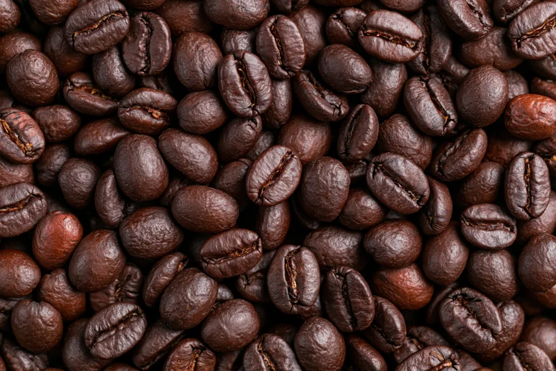 Hundreds of dark roasted coffee beans filling the frame