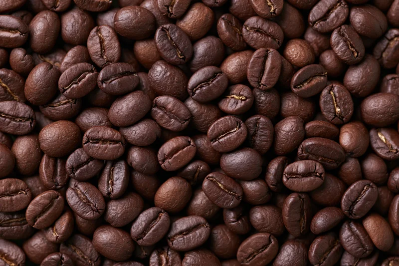 Hundreds of whole roasted coffee beans filling the entire frame