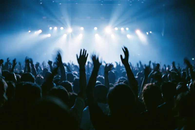 Crowd at concert with hands raised toward bright stage lights
