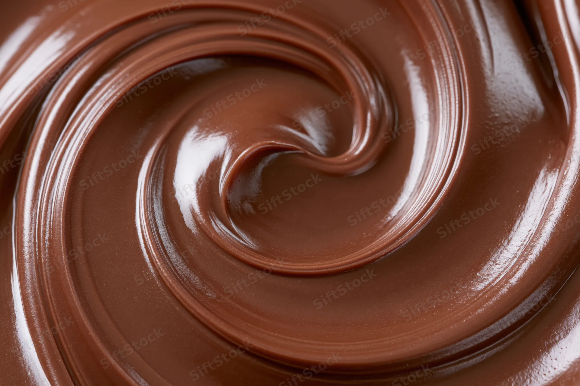 Melted dark chocolate swirled into a smooth spiral pattern closeup