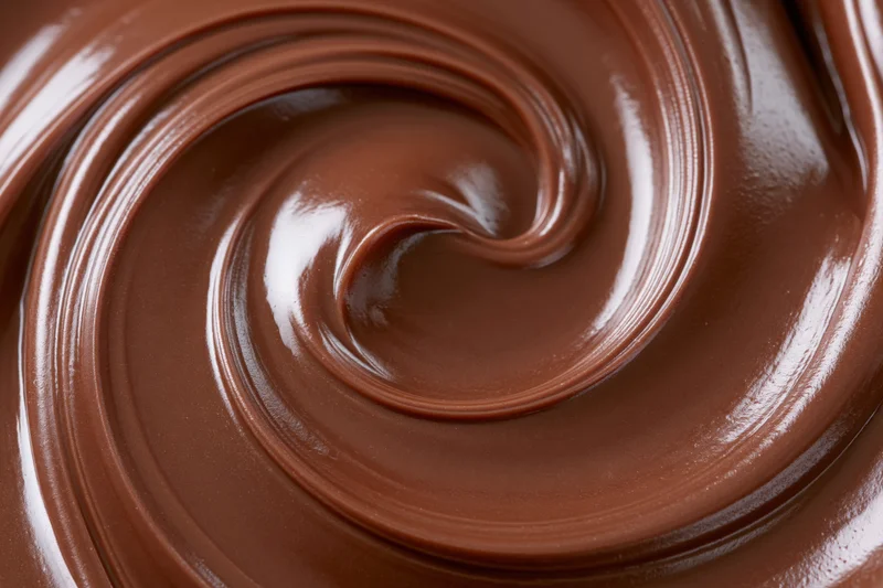 Melted dark chocolate swirled into a smooth spiral pattern closeup