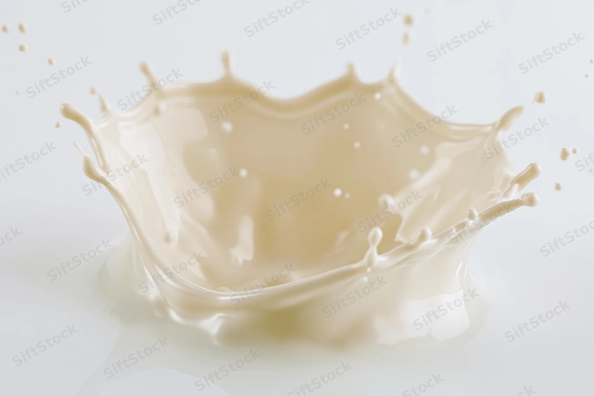 Cream splash frozen mid-motion forming a dynamic crown shape on white background