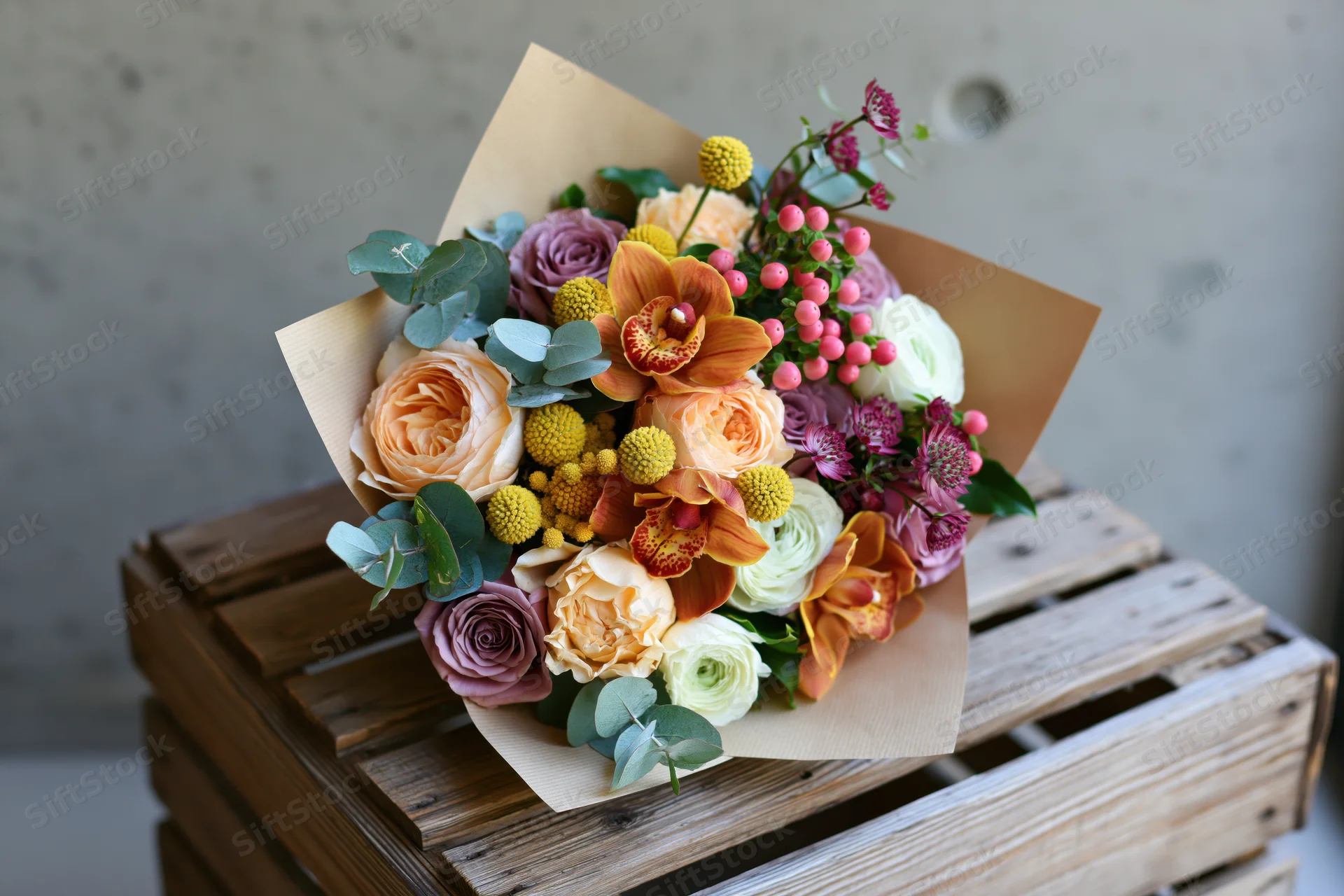 Mixed flower bouquet wrapped in kraft paper resting on wooden crate