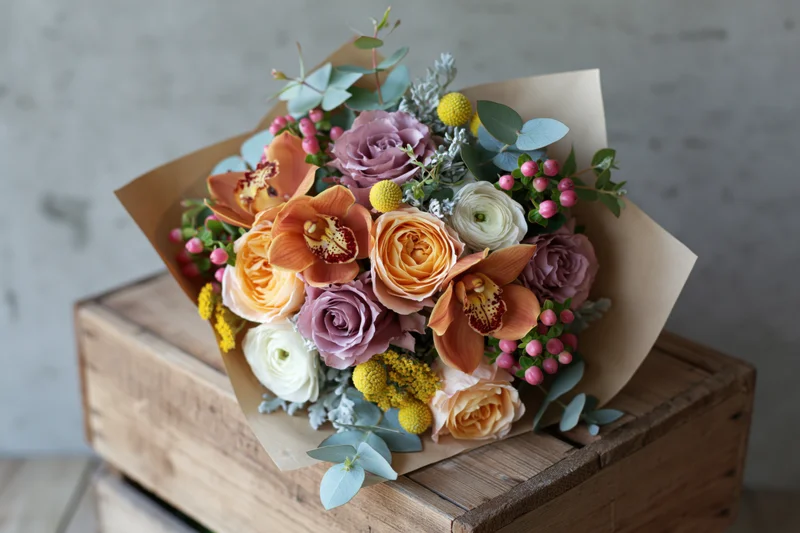Mixed flower bouquet wrapped in kraft paper resting on wooden crate