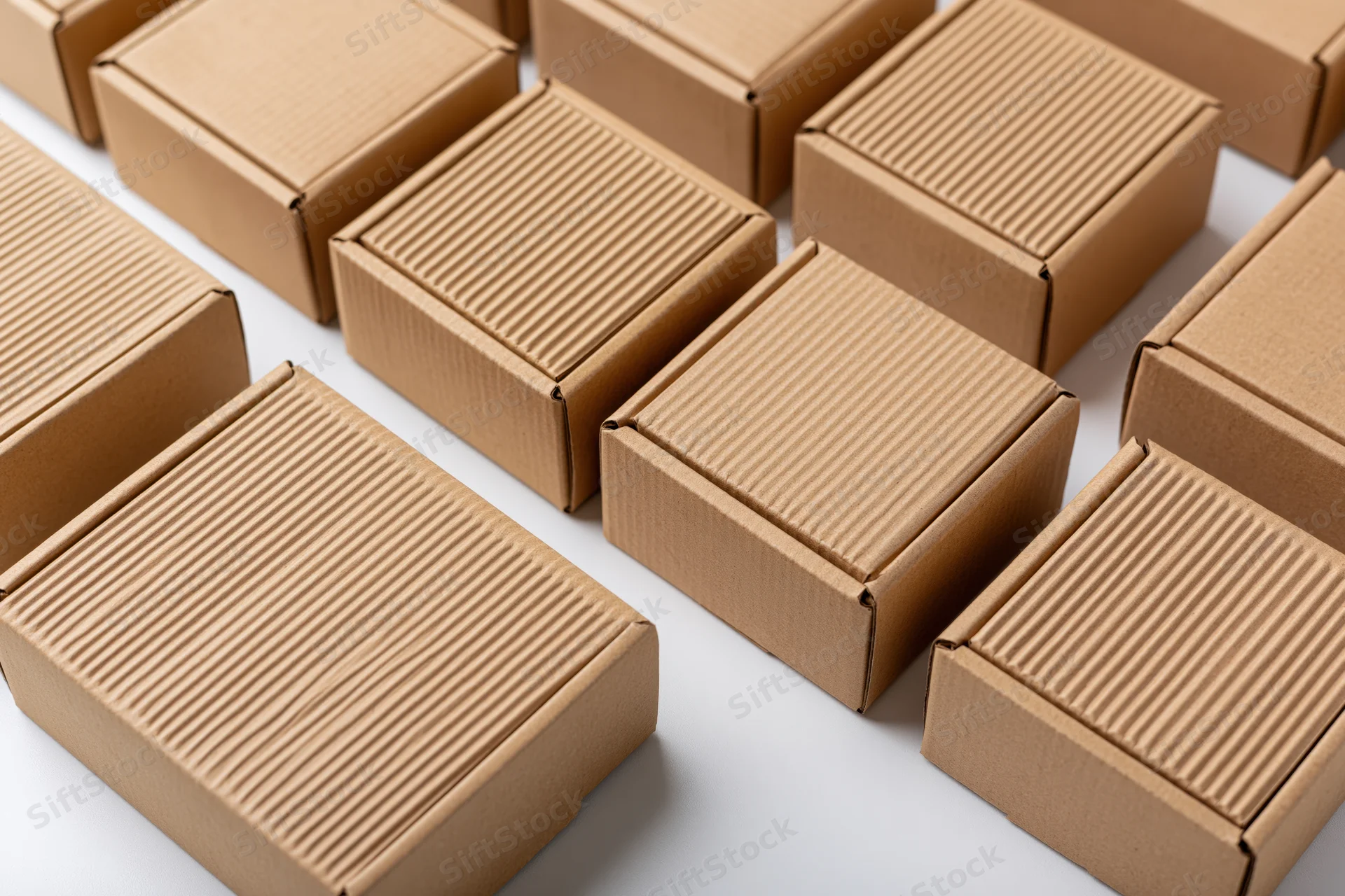 Multiple closed kraft cardboard shipping boxes arranged in rows on a white surface