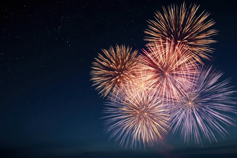 Fireworks bursting in the night sky with stars visible in the background