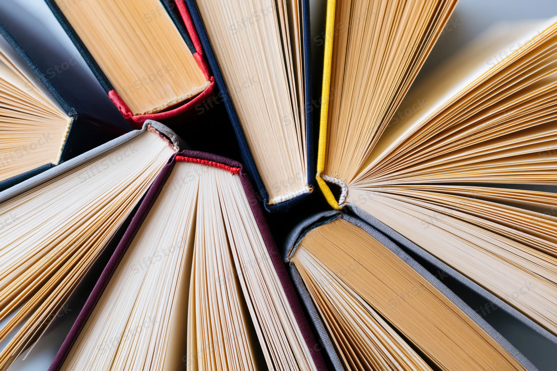 Multiple hardcover books fanned open showing pages and spines in a circular arrangement