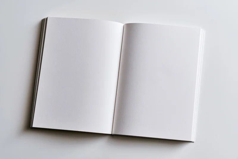 Open blank notebook with empty white pages lying flat on a white surface