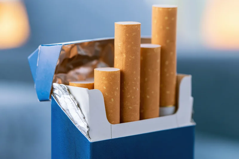 Open blue cigarette pack with several cigarettes protruding, close-up view