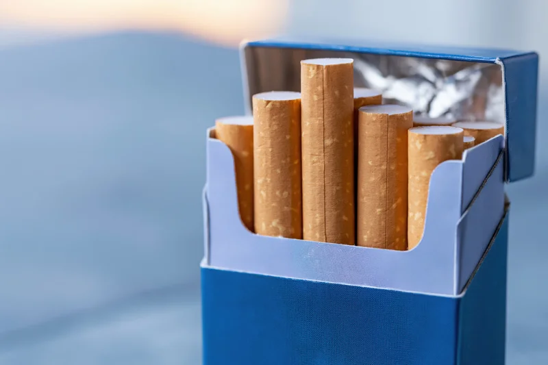 Open blue cigarette pack with several cigarettes protruding, close-up view