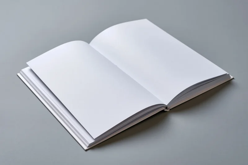 Open hardcover book with blank white pages lying flat on gray surface