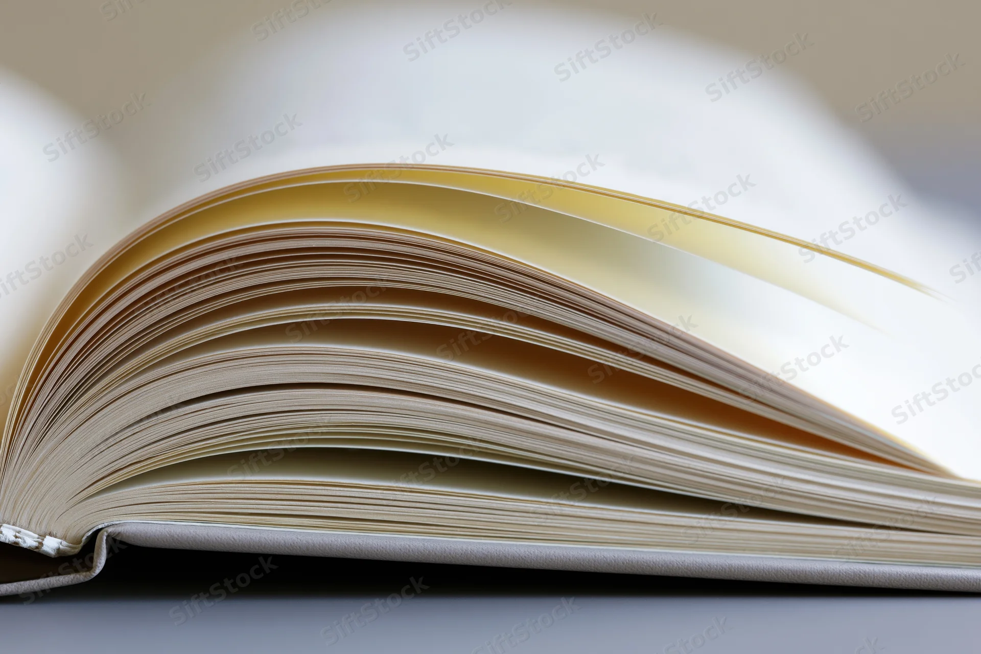 Open hardcover book with pages fanned wide on a flat surface