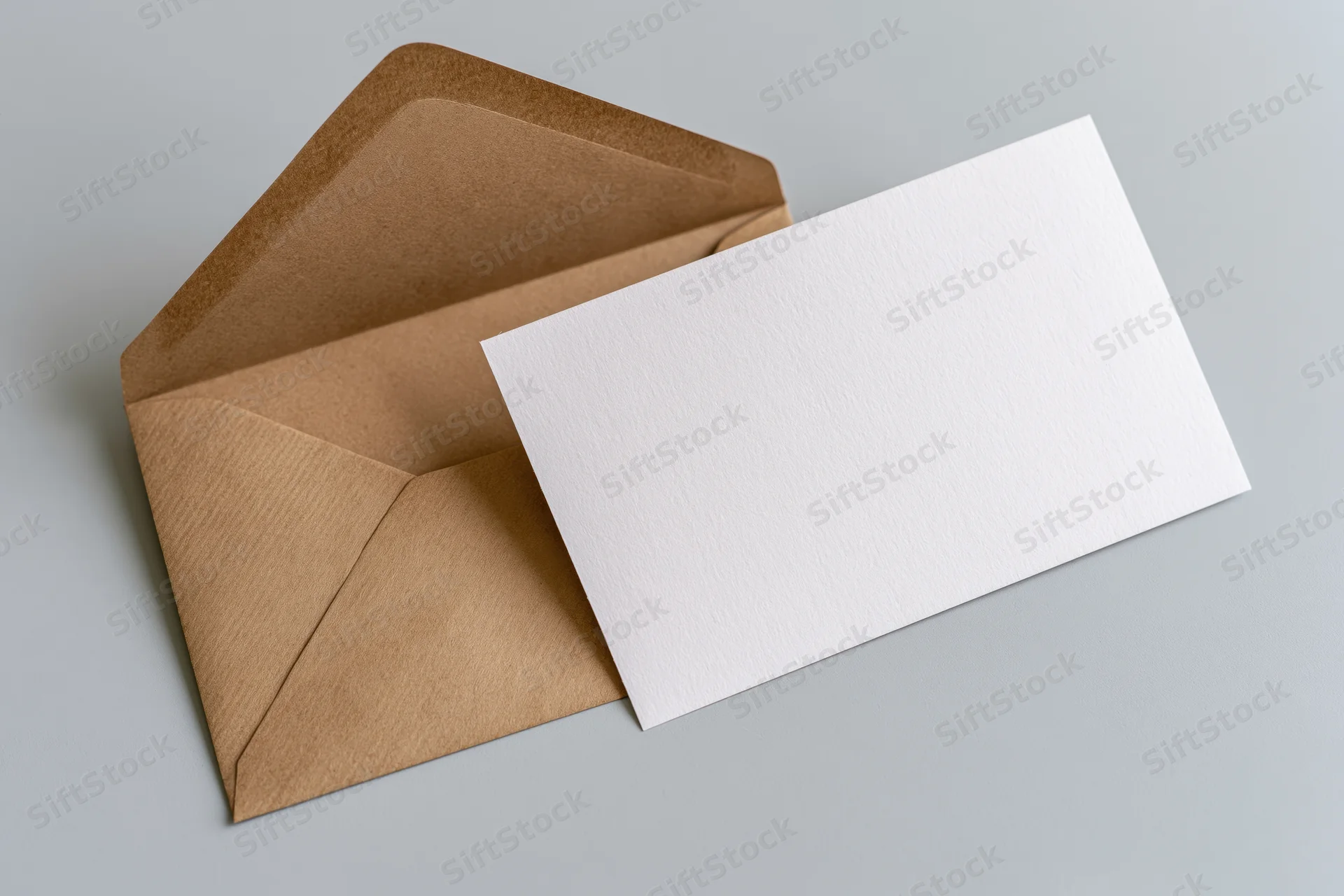 Open kraft paper envelope with blank white card resting on gray surface