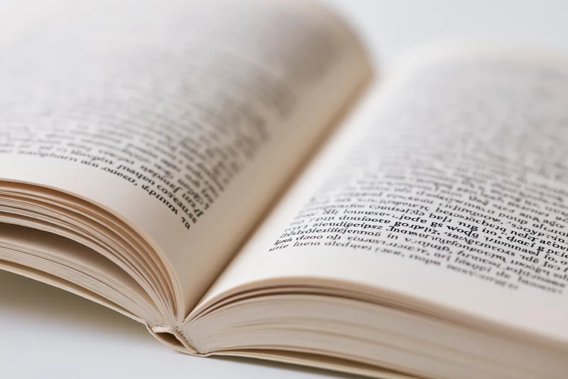 Open paperback book with pages spread apart on white surface