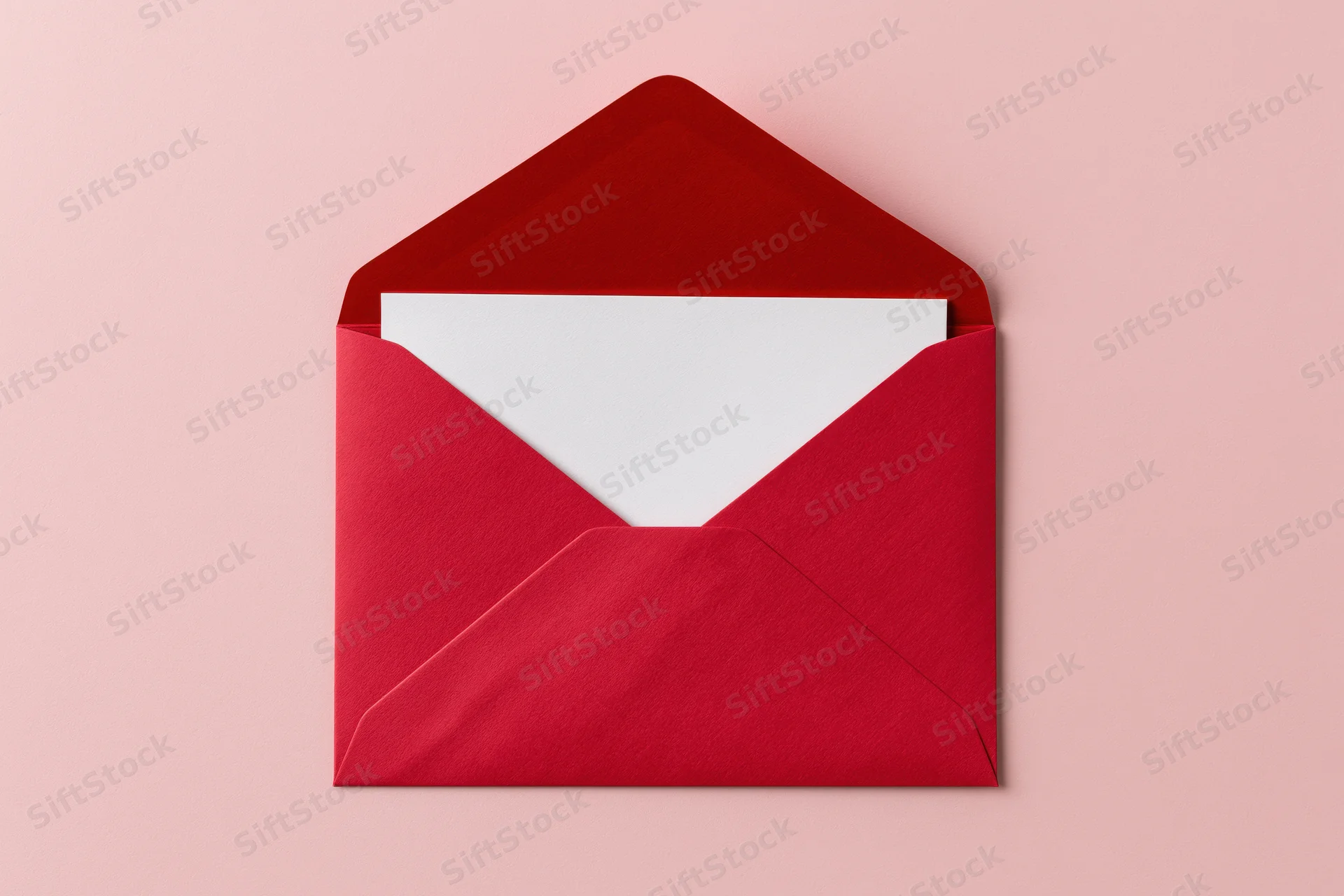 Open red paper envelope with blank white card inside on pink background