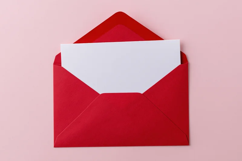 Open red paper envelope with blank white card inside on pink background