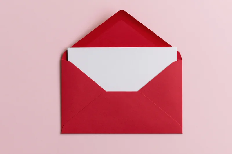 Open red paper envelope with blank white card inside on pink background
