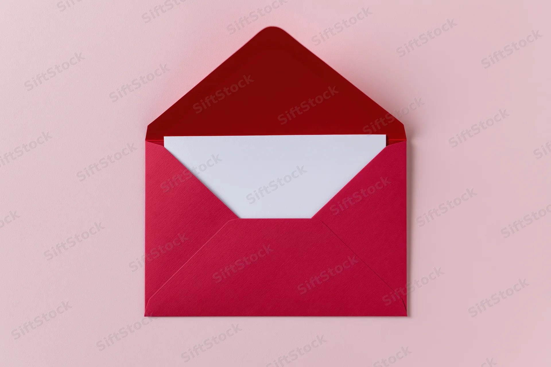 Open red paper envelope with blank white card inside on pink background