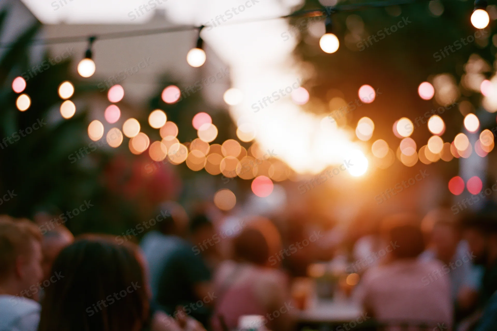 People gathered outdoors at evening under string lights for a social event