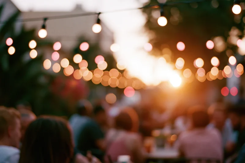People gathered outdoors at evening under string lights for a social event