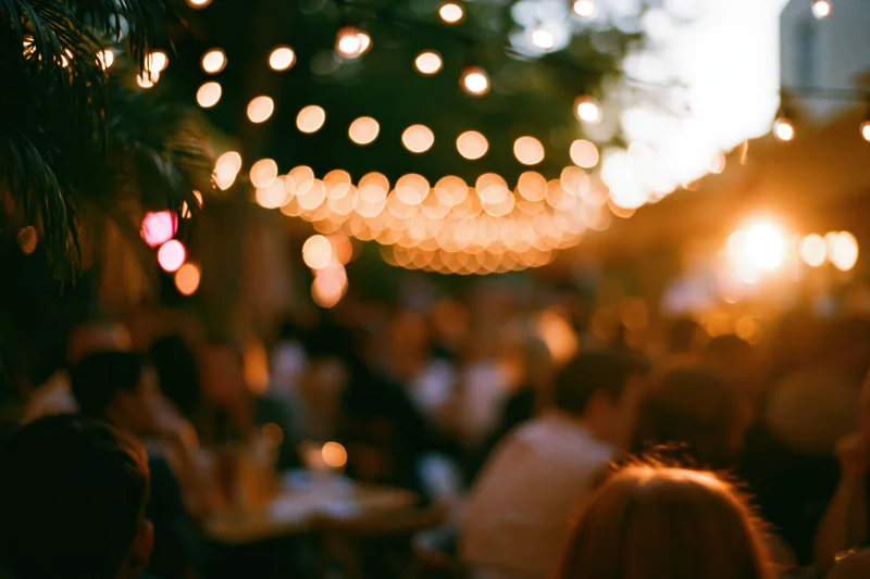 Crowd gathered outdoors under string lights at evening event