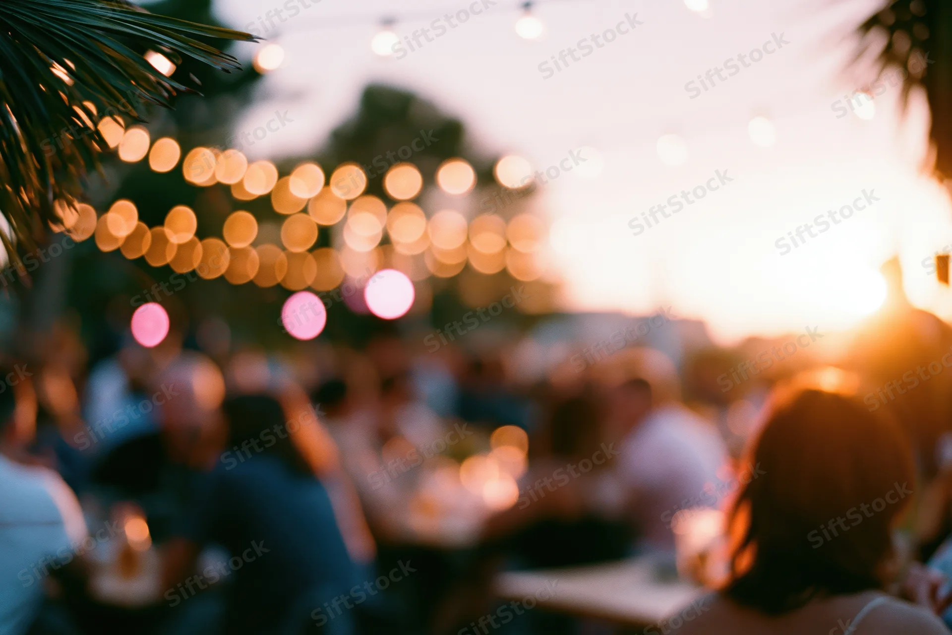 People gathered outdoors at dusk under string lights for a social event