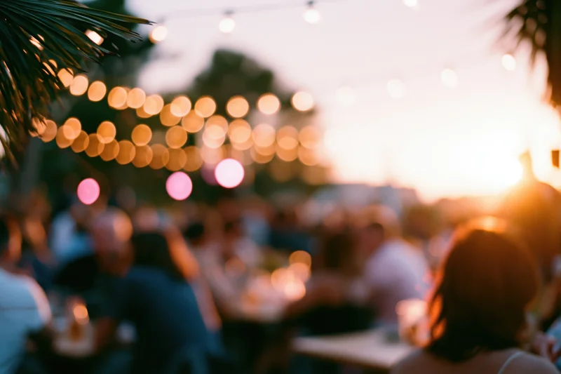 People gathered outdoors at dusk under string lights for a social event