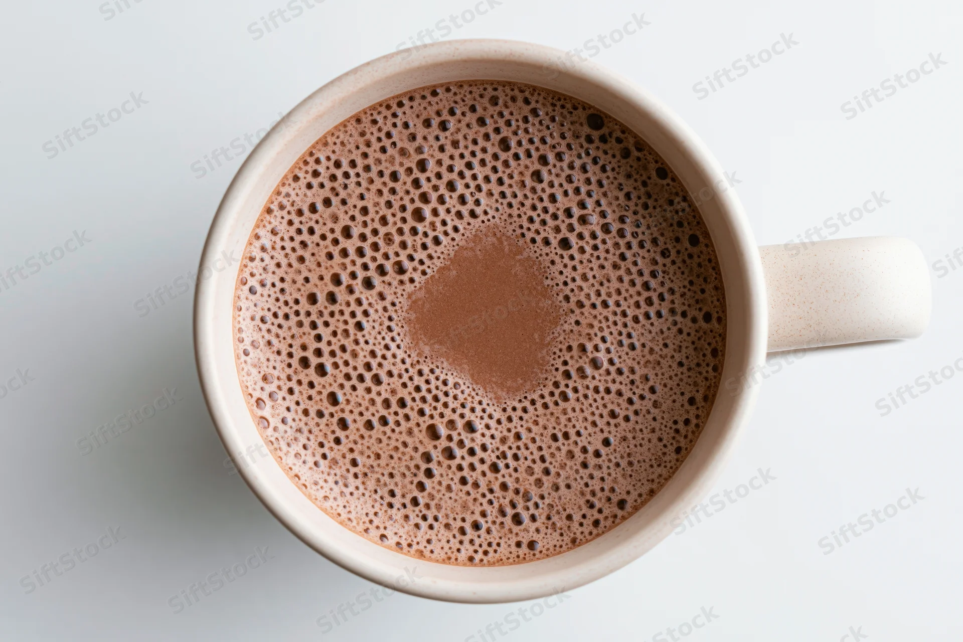 Overhead view of a white ceramic mug filled with frothy hot chocolate on a plain surface