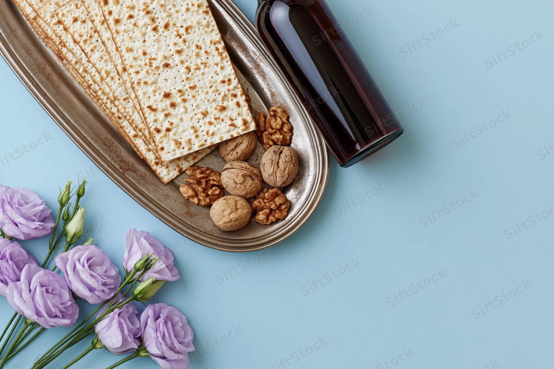 Matzah crackers and wine on a tarnished tray with walnuts and lilac flowers for passover seder flat lay