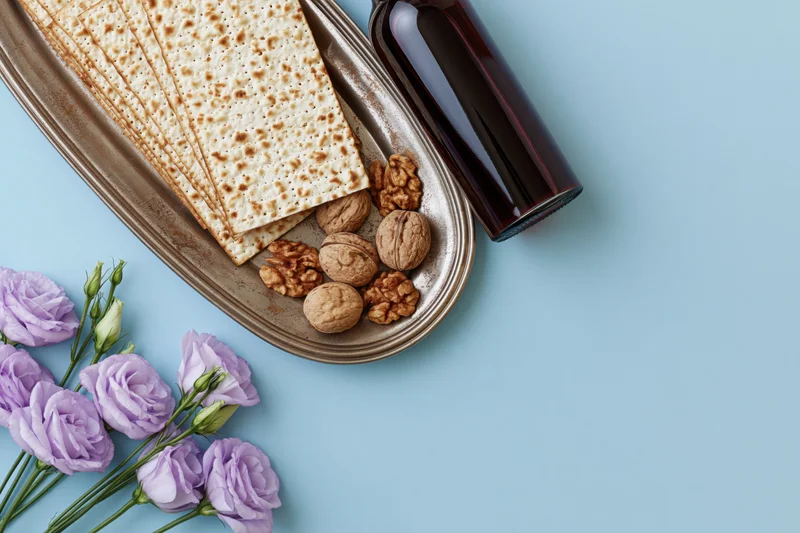 Matzah crackers and wine on a tarnished tray with walnuts and lilac flowers for passover seder flat lay