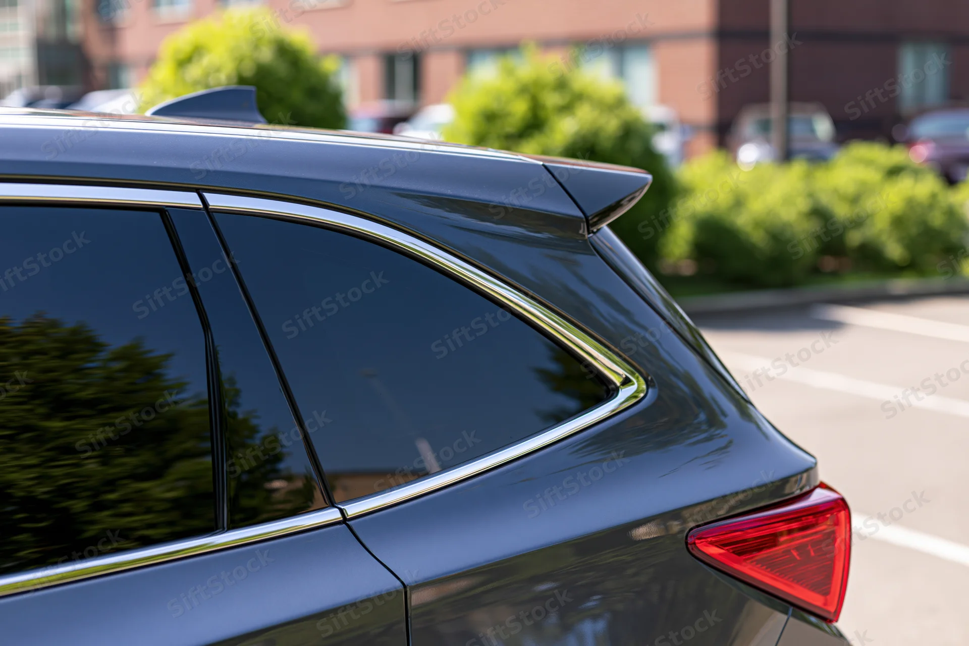 Rear view of a dark grey suv parked outdoors showing chrome trim and spoiler